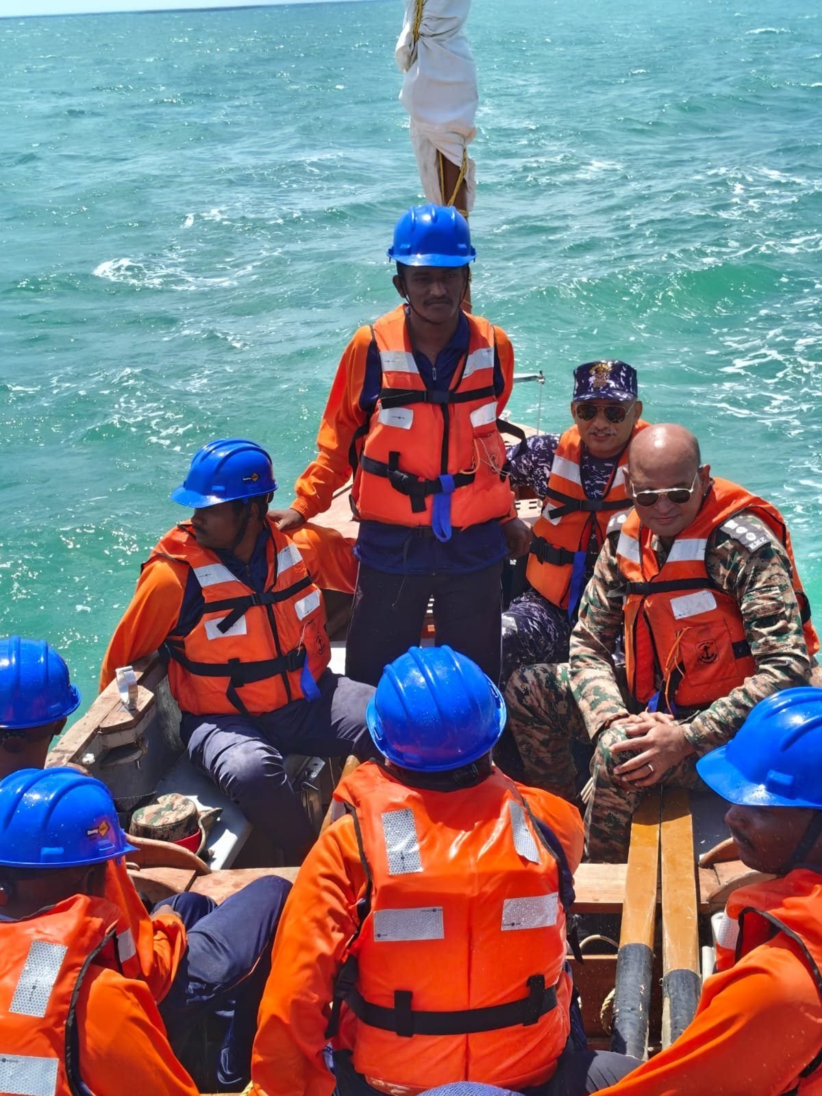 Cadets and staff aboard the whaler at sea, wearing helmets and life jackets