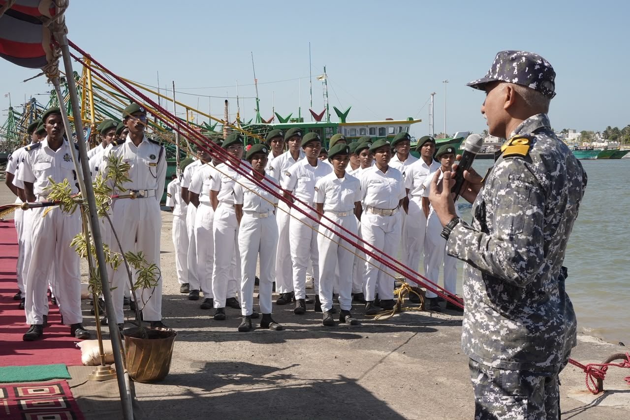 A naval officer briefing assembled cadets on a pier
