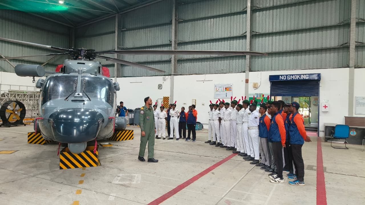Cadets receiving a briefing beside a Navy helicopter inside a hangar
