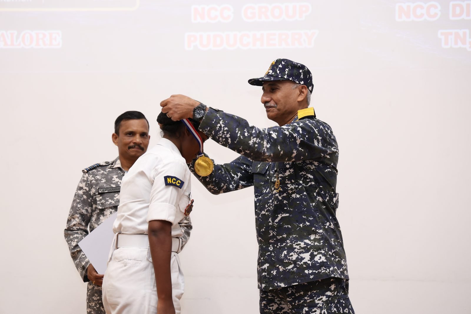 Naval officer placing a medal on a cadet at the closing ceremony