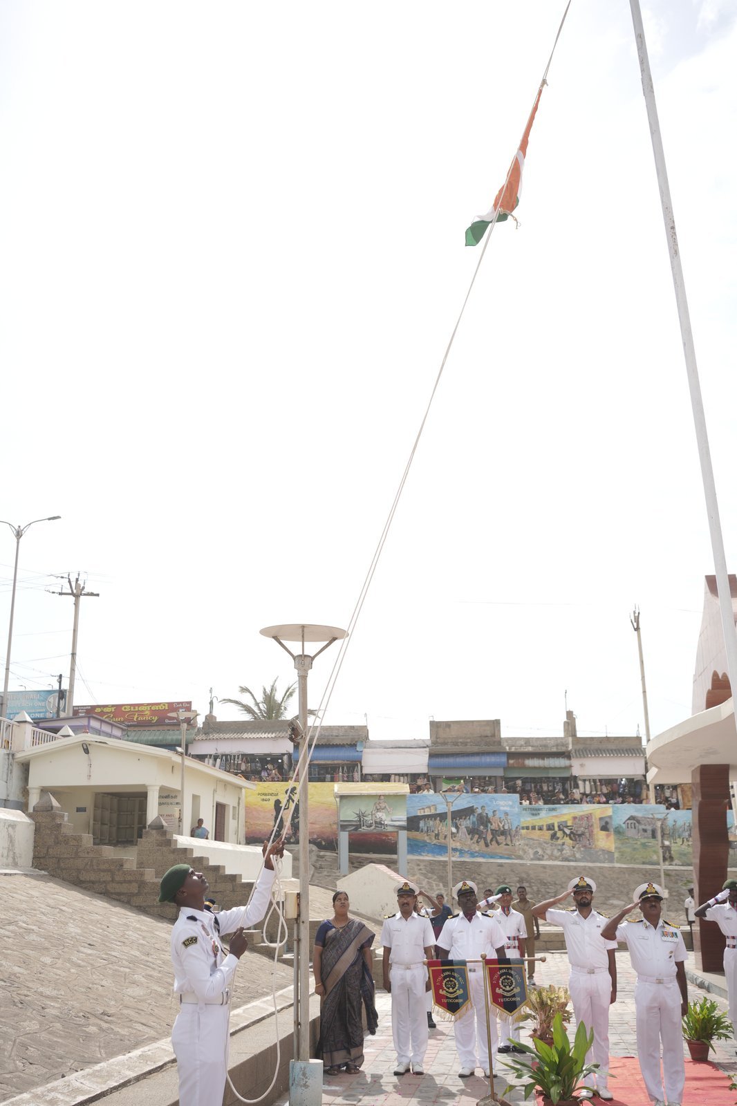 NCC cadet raising the national flag at the Gandhi Memorial, with naval officers standing to attention