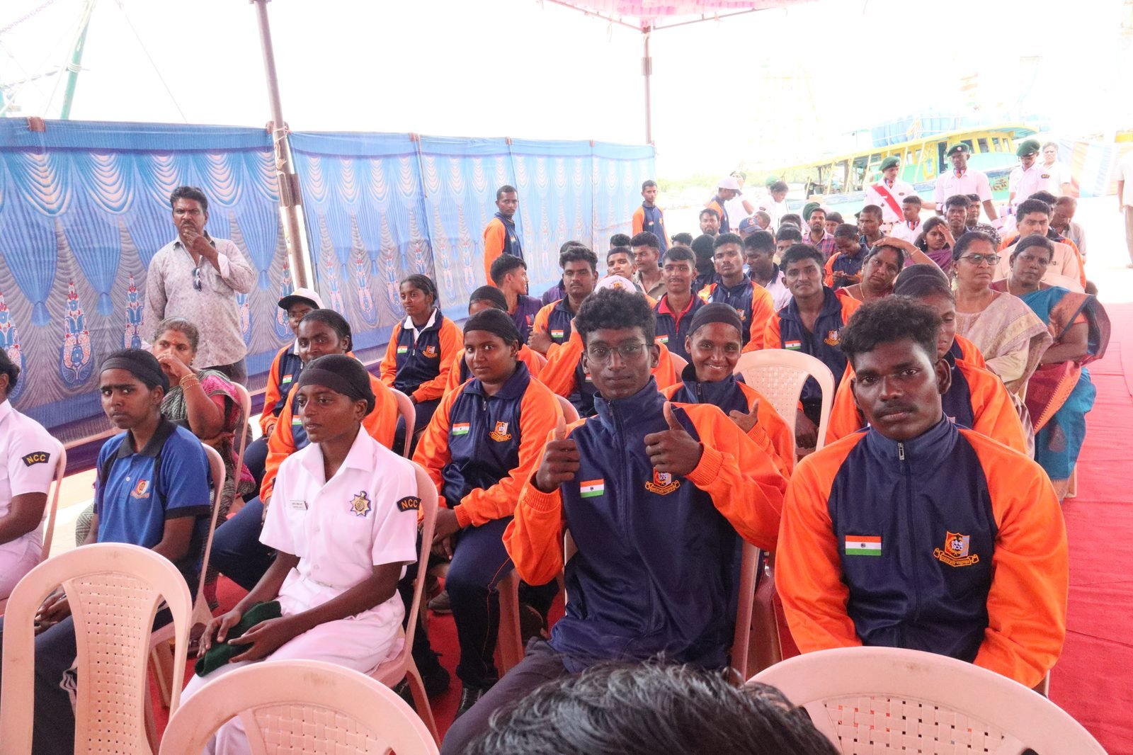 NCC cadets seated in audience wearing orange-blue expedition jackets
