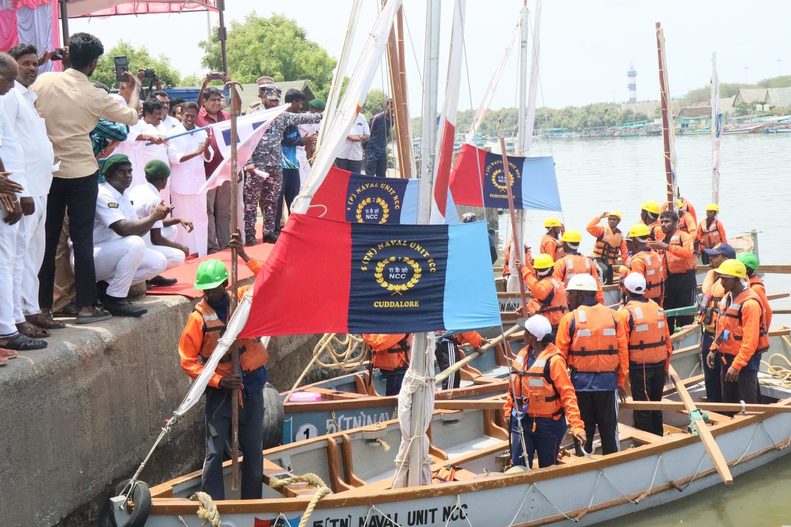 Cadets in boats at pier with NCC Naval Unit Cuddalore and Puducherry banners, wearing life jackets