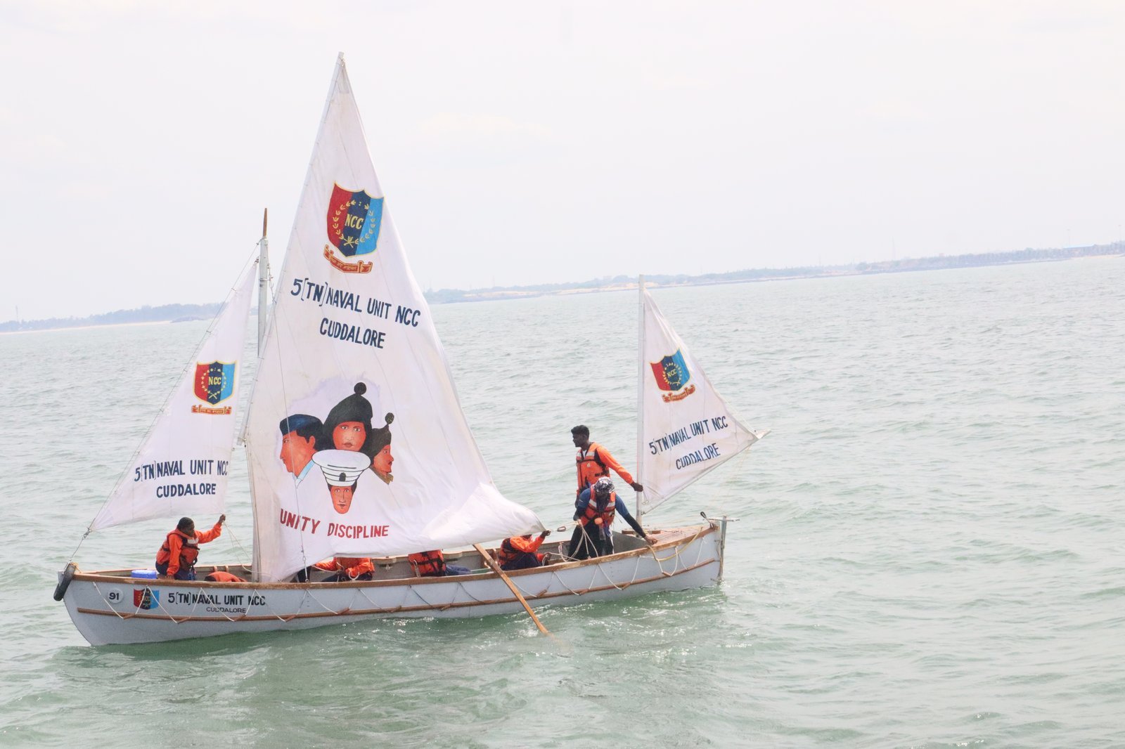 NCC cadets under sail in a Cuddalore unit whaler, painted sails displaying UNITY DISCIPLINE