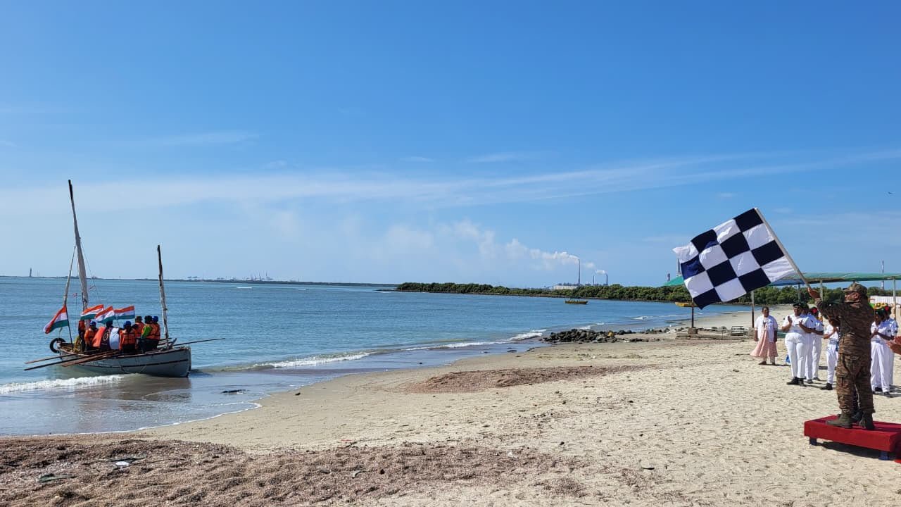 Sailboat approaching the Thoothukudi beach while a checkered flag is waved to welcome the crew